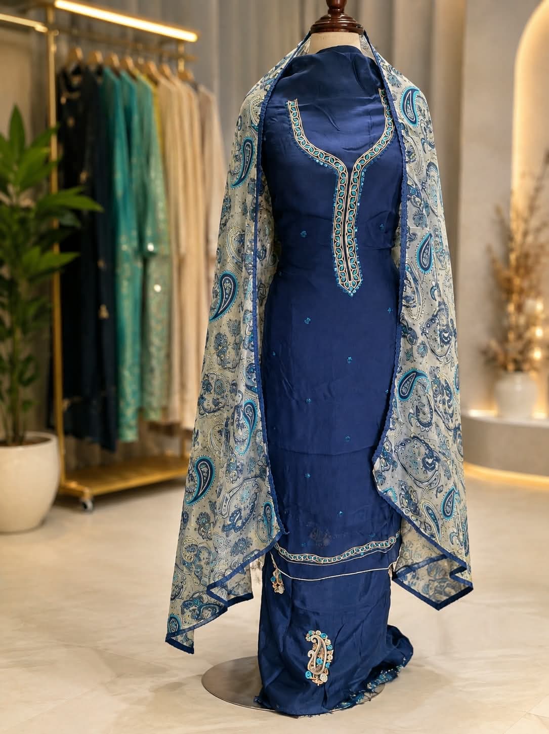 A navy blue kurta with a multi-coloured embroidered neckline and scattered mirror-work, worn with a cream and olive paisley-printed dupatta edged in navy lace
