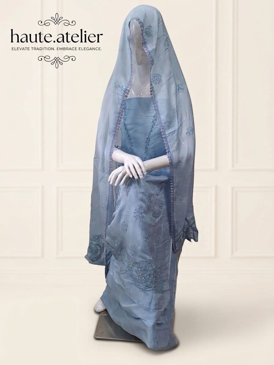 A sheer sky-blue organza suit with tone-on-tone thread embroidery and cutwork, the lace-edged dupatta draped over the head